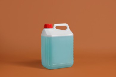 Photo of Plastic canister with blue liquid on brown background