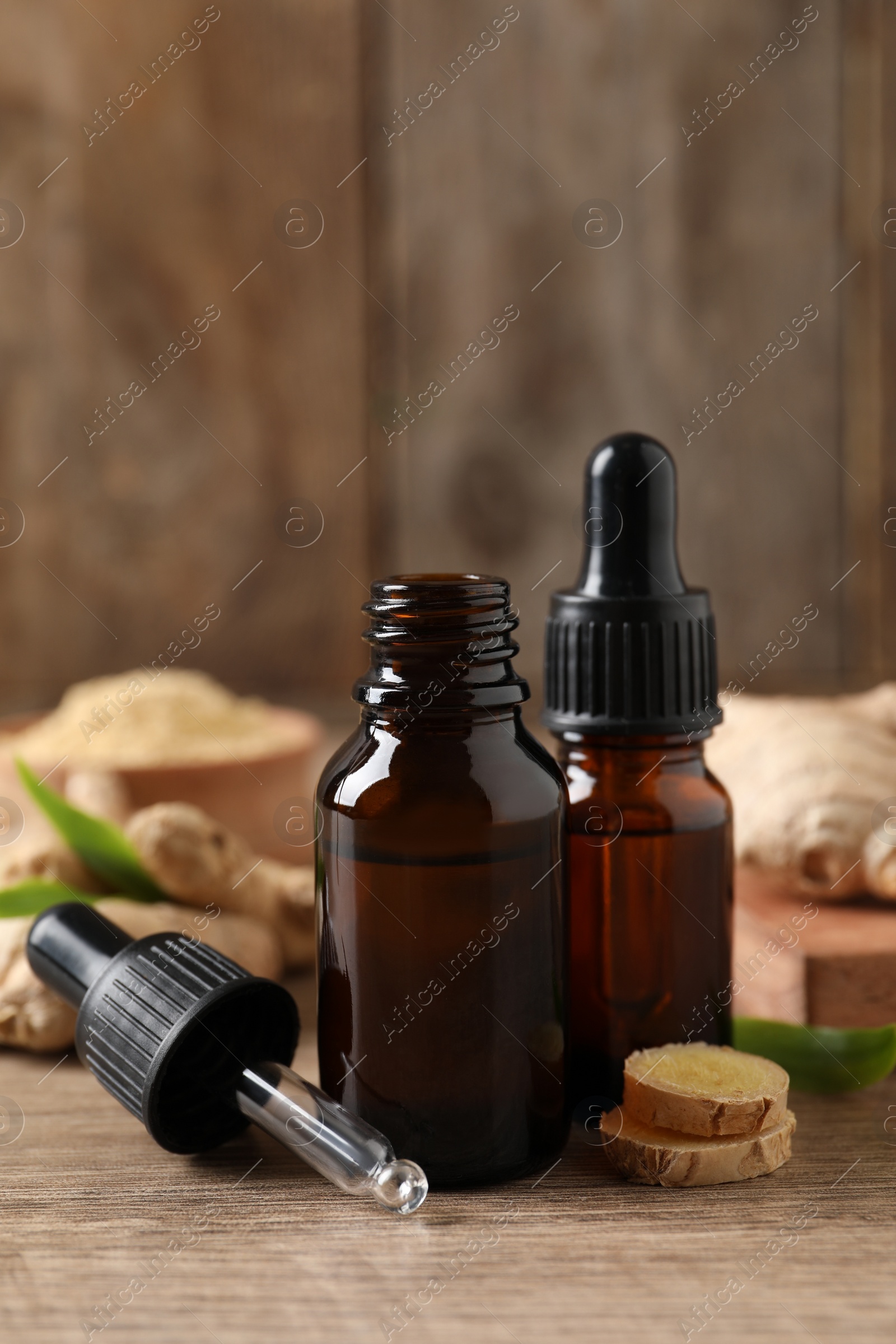 Photo of Ginger essential oil in bottles on wooden table