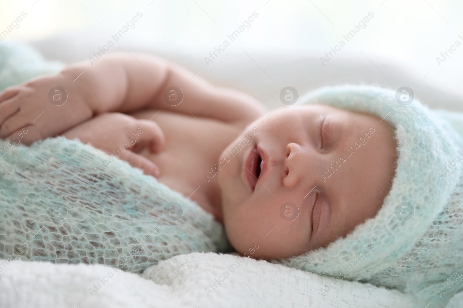 Photo of Cute newborn baby in warm hat sleeping on white plaid, closeup