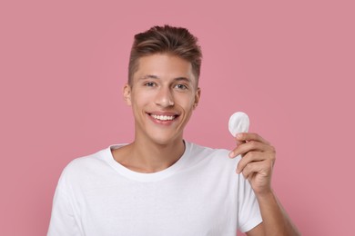 Handsome man with cotton pad on pink background