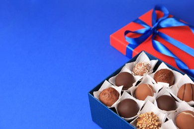 Photo of Box with delicious chocolate candies on blue background, closeup