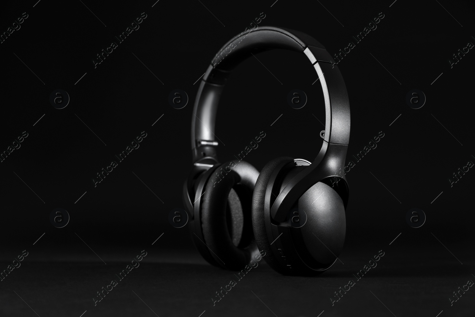 Photo of Stylish modern wireless headphones on black background