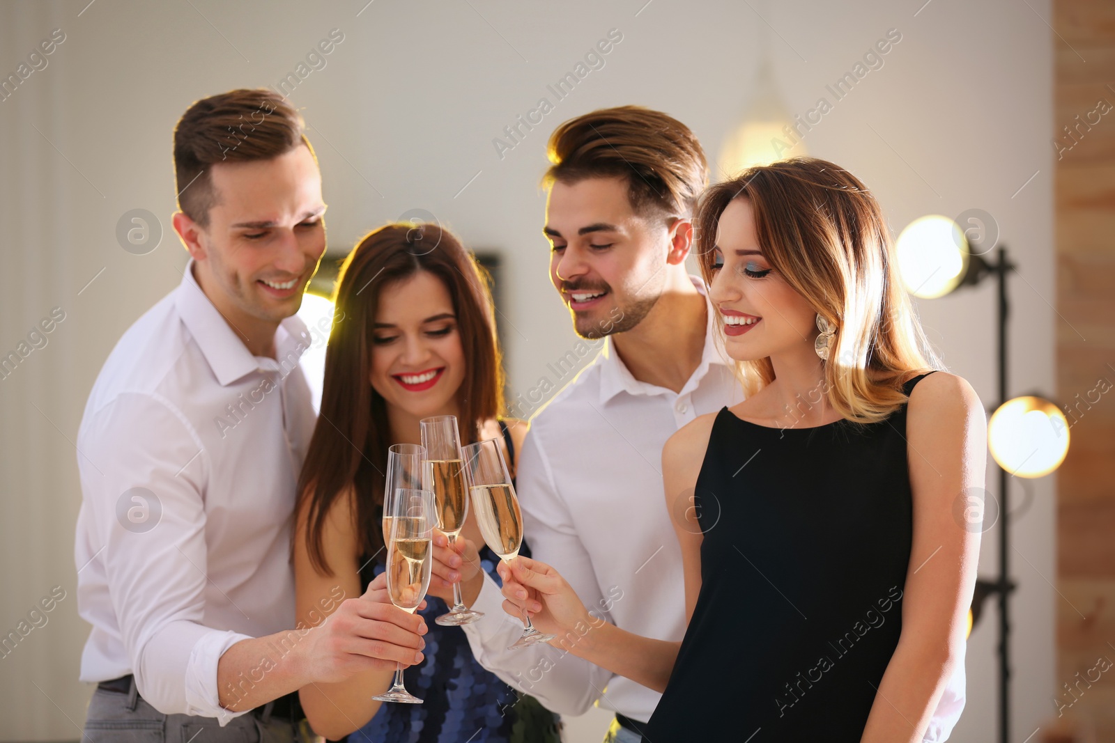 Photo of Friends clinking glasses with champagne at party indoors