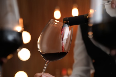 Waitress pouring wine into glass in restaurant, closeup