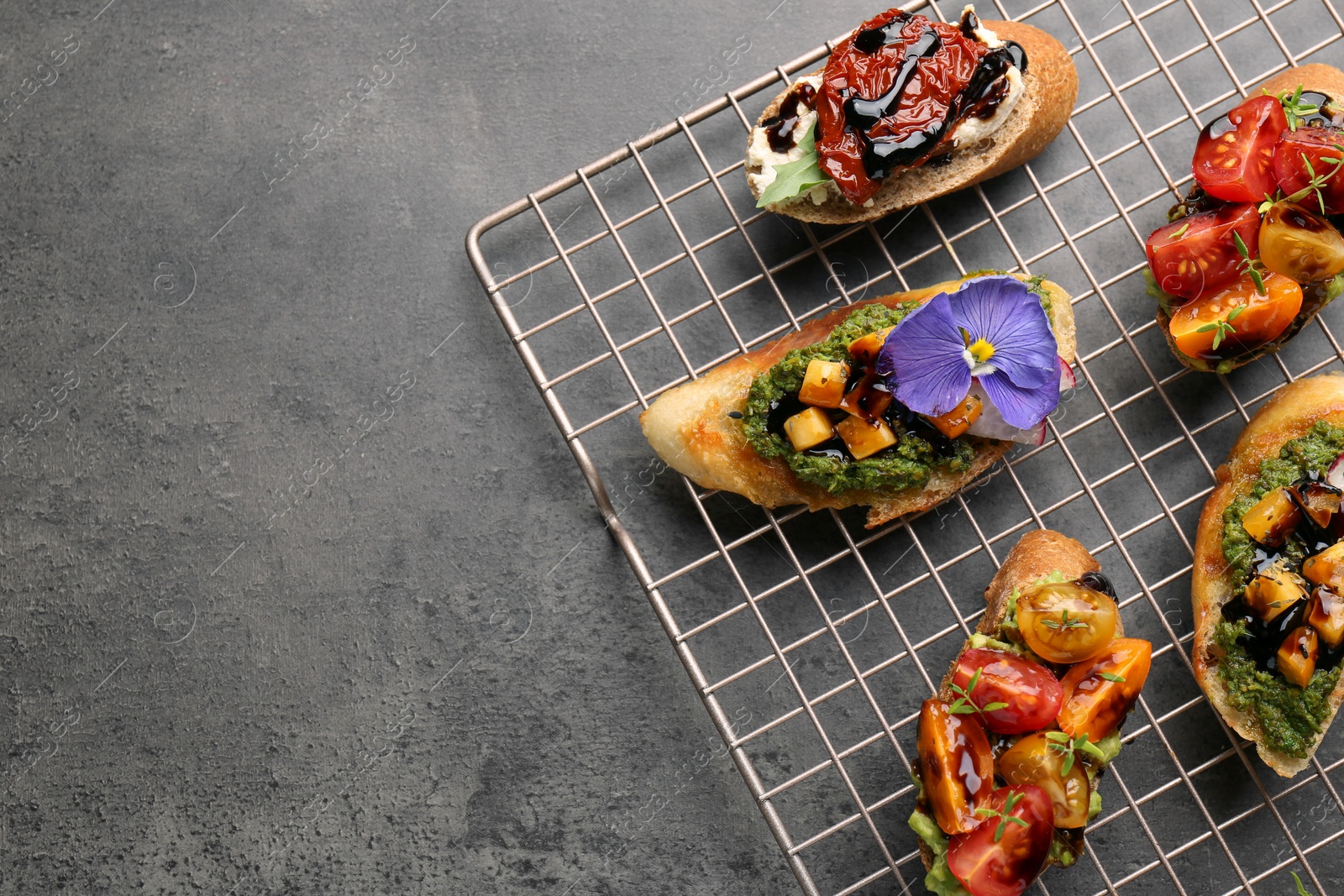 Photo of Delicious bruschettas with different toppings and balsamic vinegar on gray textured table, flat lay. Space for text