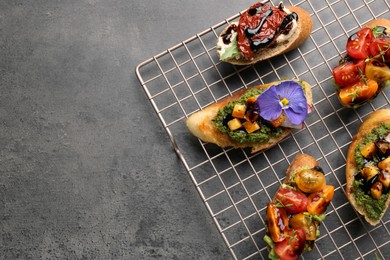 Delicious bruschettas with different toppings and balsamic vinegar on gray textured table, flat lay. Space for text