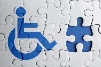 Image of Inclusion concept. White puzzle with international symbol of access and missing piece on blue background, top view