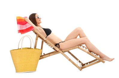 Young woman with beach accessories on sun lounger against white background
