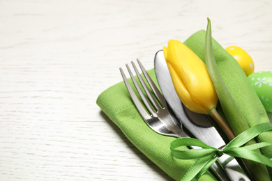 Cutlery set with beautiful tulip on white wooden table, closeup view with space for text. Easter celebration