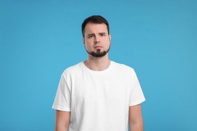 Portrait of sad man on light blue background