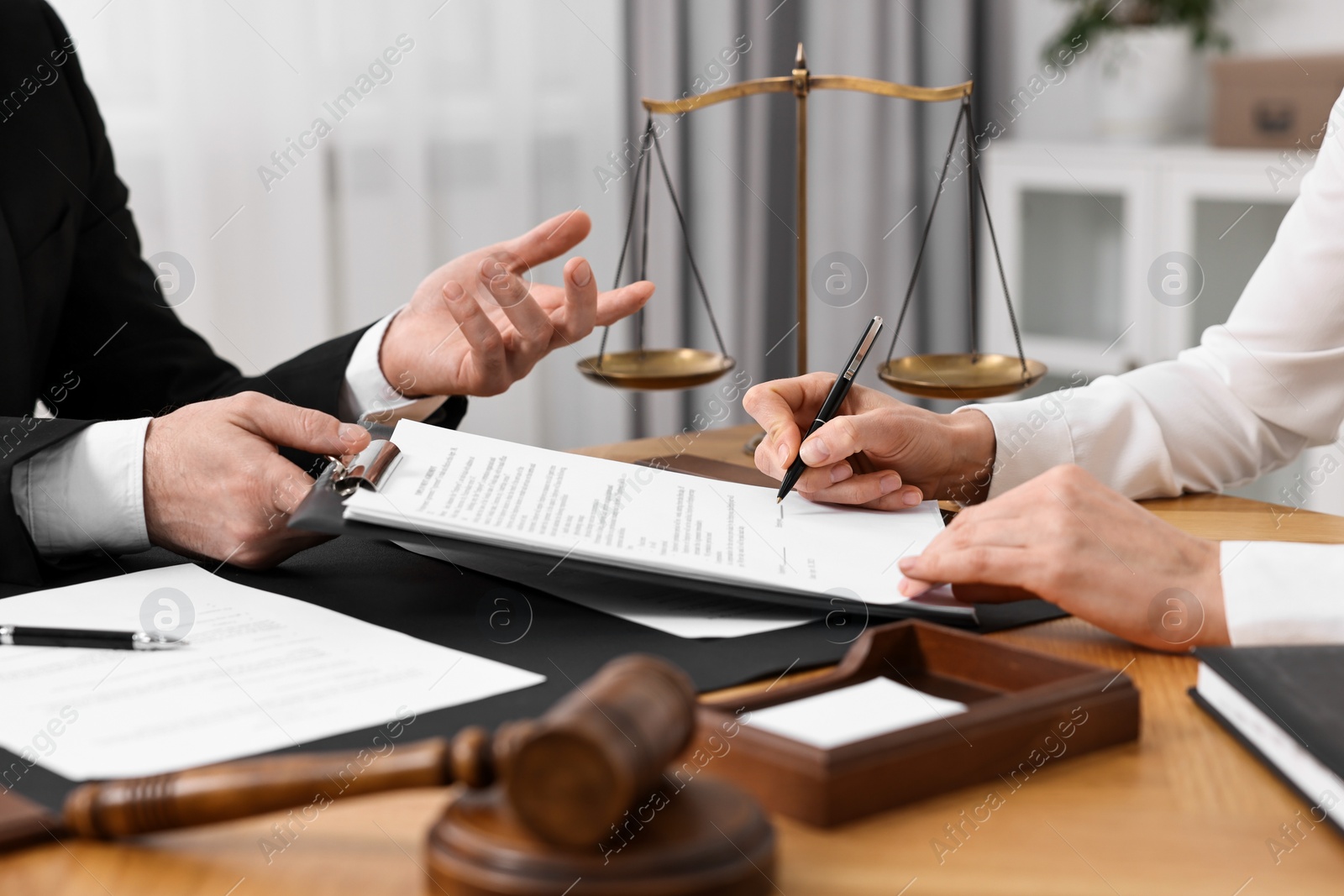 Photo of Woman signing document in lawyer's office, closeup