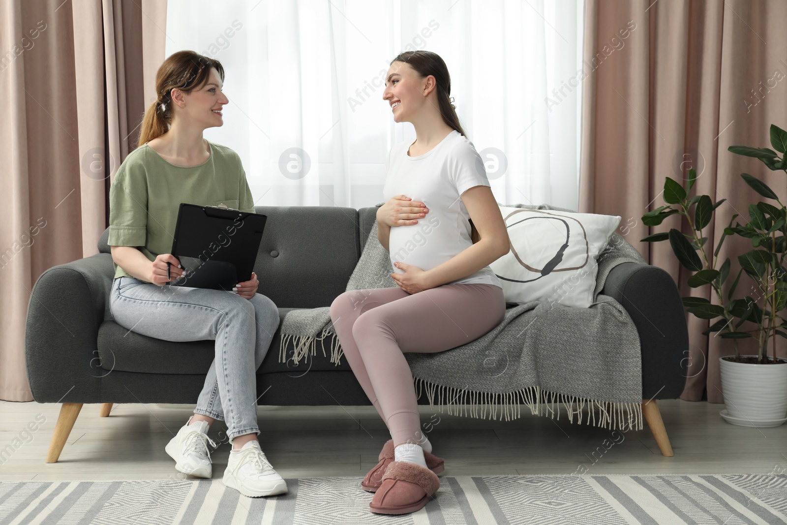 Photo of Doula working with pregnant woman on sofa at home. Preparation for child birth