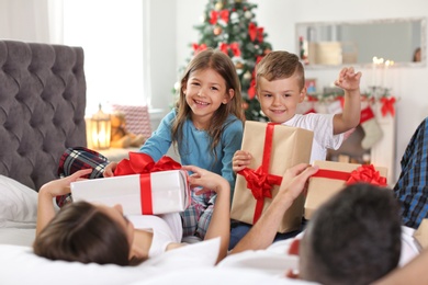 Photo of Happy parents and children with gifts celebrating Christmas at home