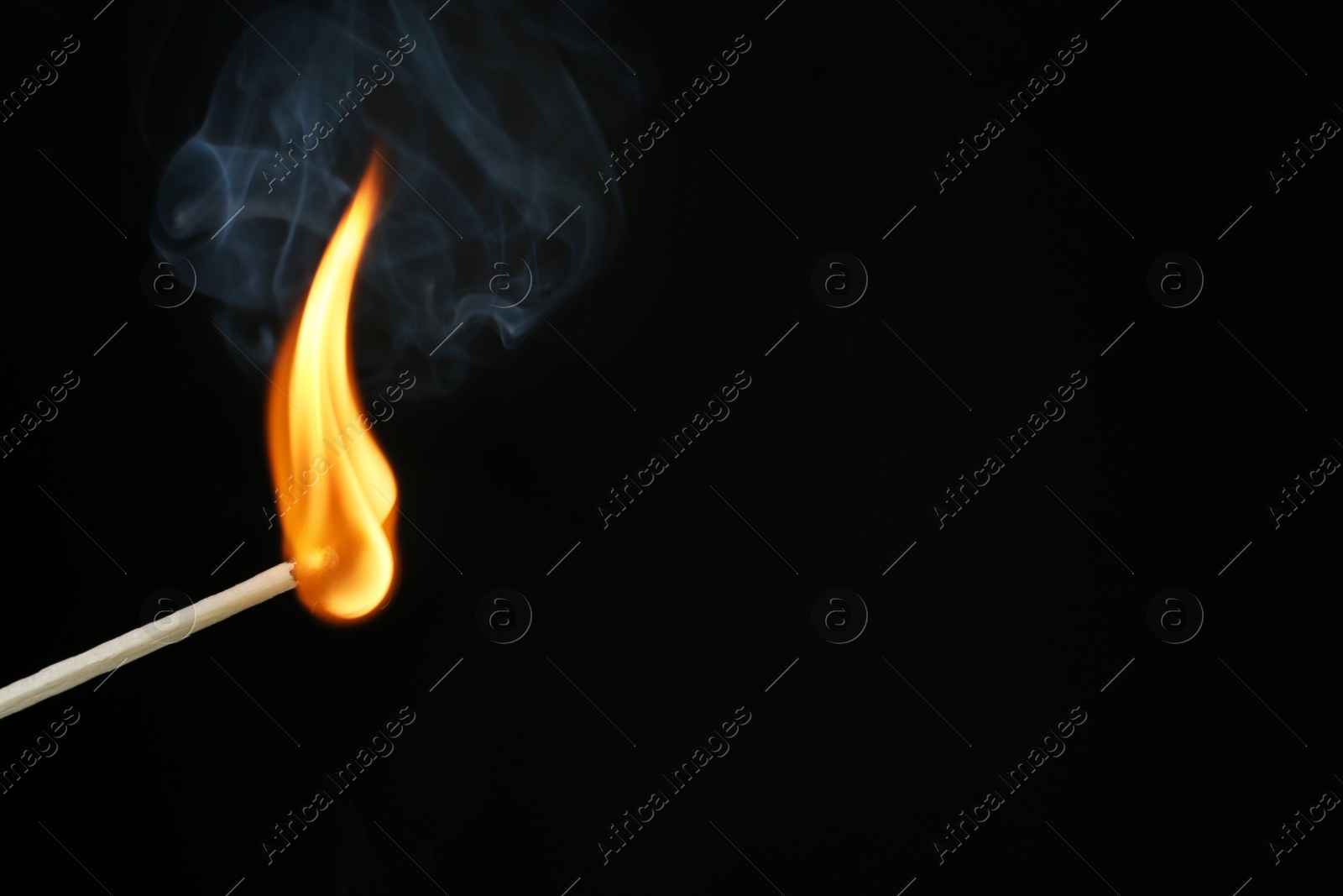 Photo of Burning matchstick on black background, closeup. Space for text