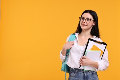 Photo of Smiling student with notebooks and clipboard on yellow background. Space for text