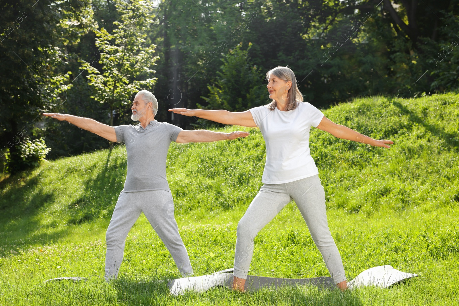 Photo of Senior couple practicing yoga on green grass in park