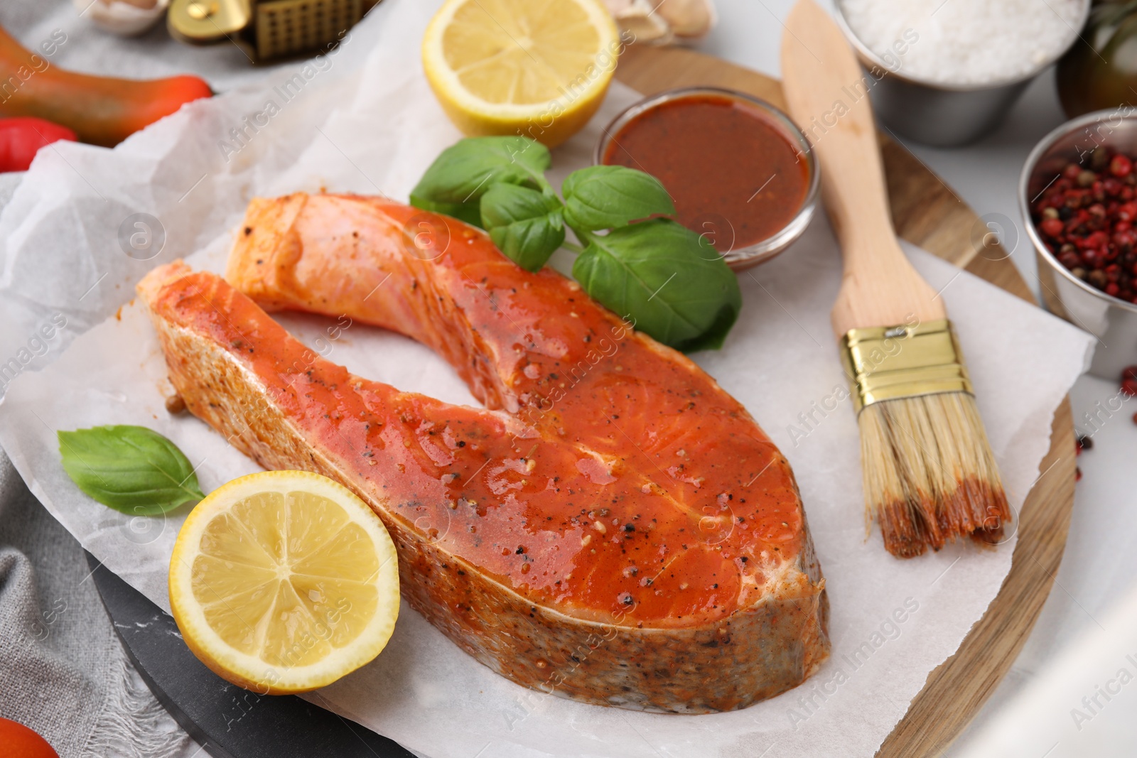 Photo of Fresh marinade, fish, lemon, brush and basil on white table