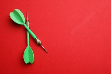 Photo of Green dart arrows on red background, flat lay with space for text