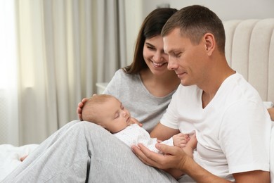 Happy family with their cute sleeping baby on bed at home