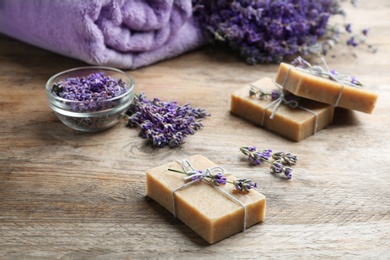 Photo of Handmade soap bars with lavender flowers on brown wooden table