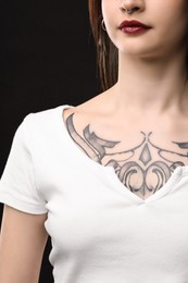 Woman with cool tattoos on black background, closeup