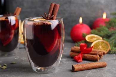 Aromatic mulled wine and ingredients on grey table, closeup. Space for text