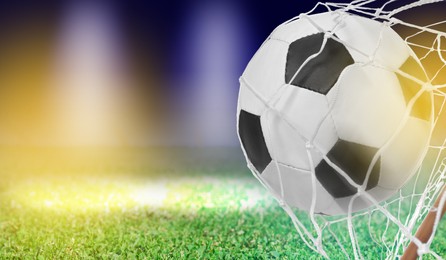 Image of Soccer ball in net and football field on color background, space for text