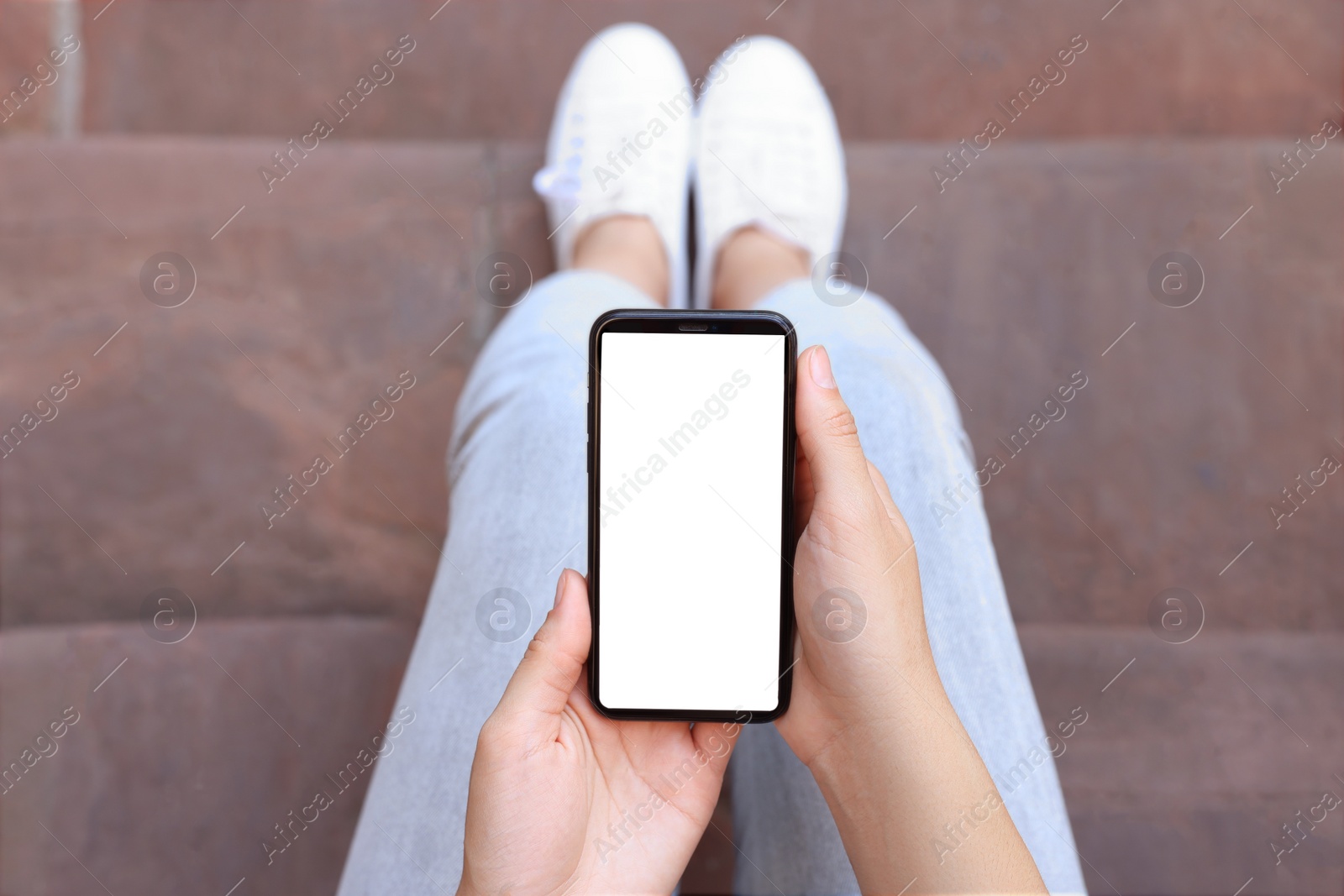 Photo of Closeup of woman using smartphone outdoors, top view