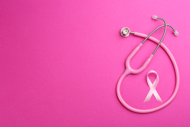 Pink ribbon as breast cancer awareness symbol and stethoscope on color background, flat lay. Space for text