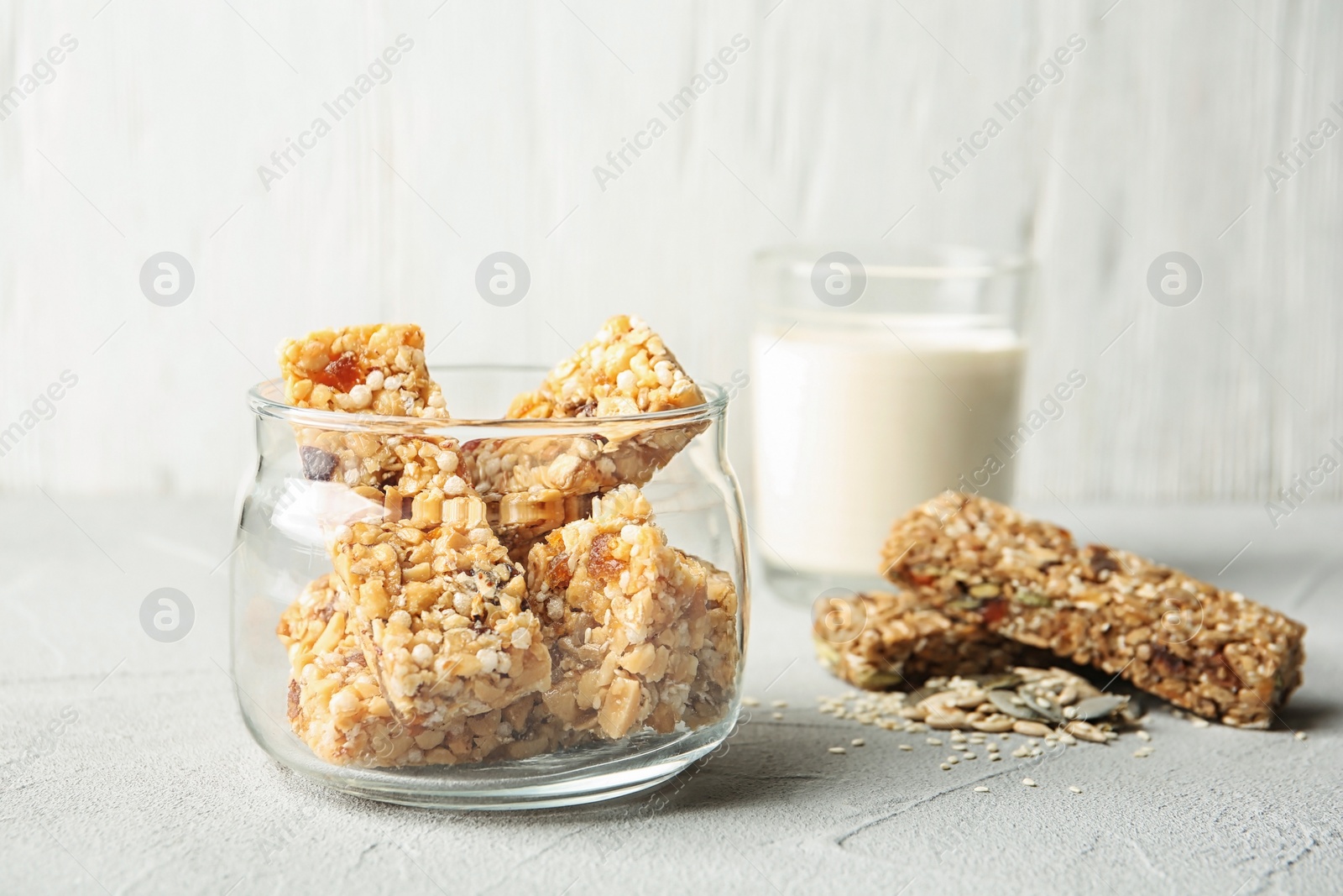 Photo of Jar with different homemade grain cereal bars on table. Healthy snack