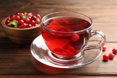 Tasty hot cranberry tea in glass cup and fresh berries on wooden table