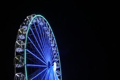 Beautiful glowing Ferris wheel against dark sky. Space for text