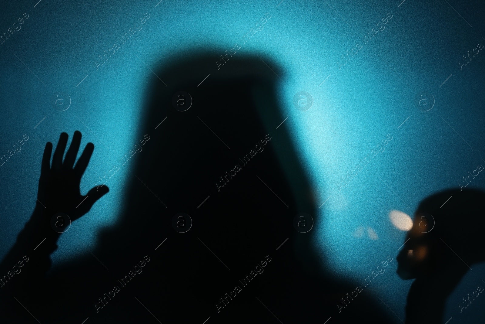 Photo of Silhouette of ghost behind glass against blue background