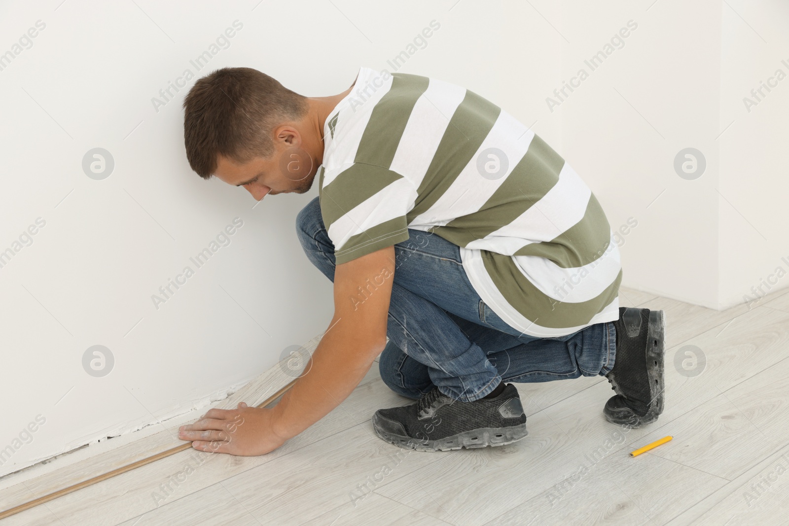 Photo of Professional worker installing new laminate flooring indoors