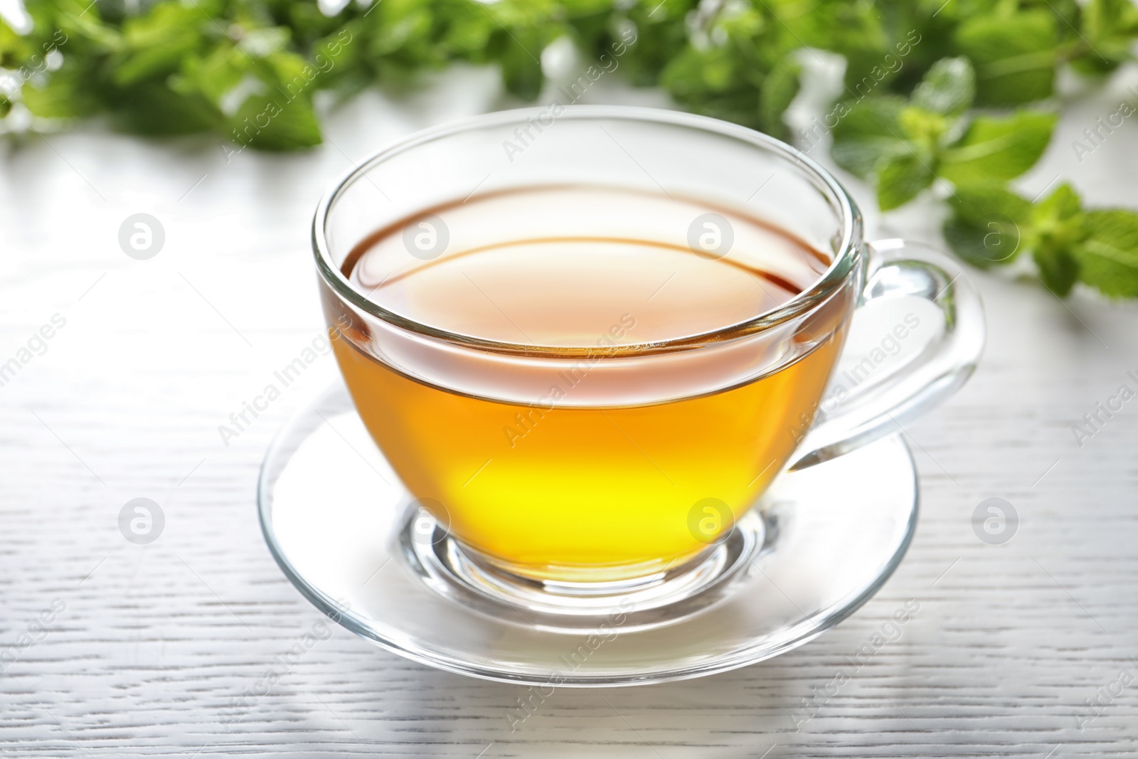 Photo of Cup with hot aromatic mint tea on table