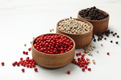 Photo of Aromatic spice. Different peppers in bowls on white table, closeup