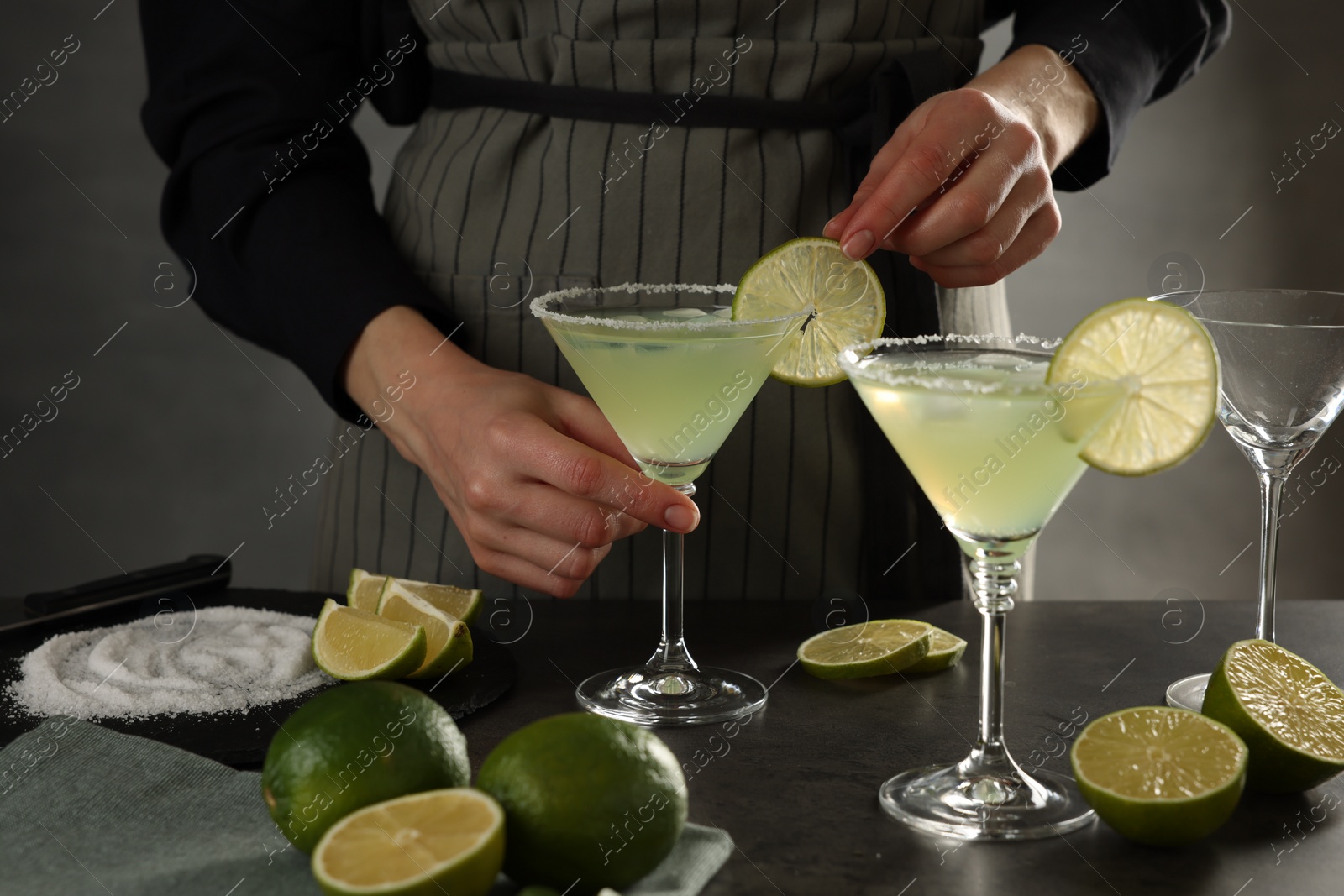 Photo of Woman making delicious Margarita cocktail at grey table, closeup