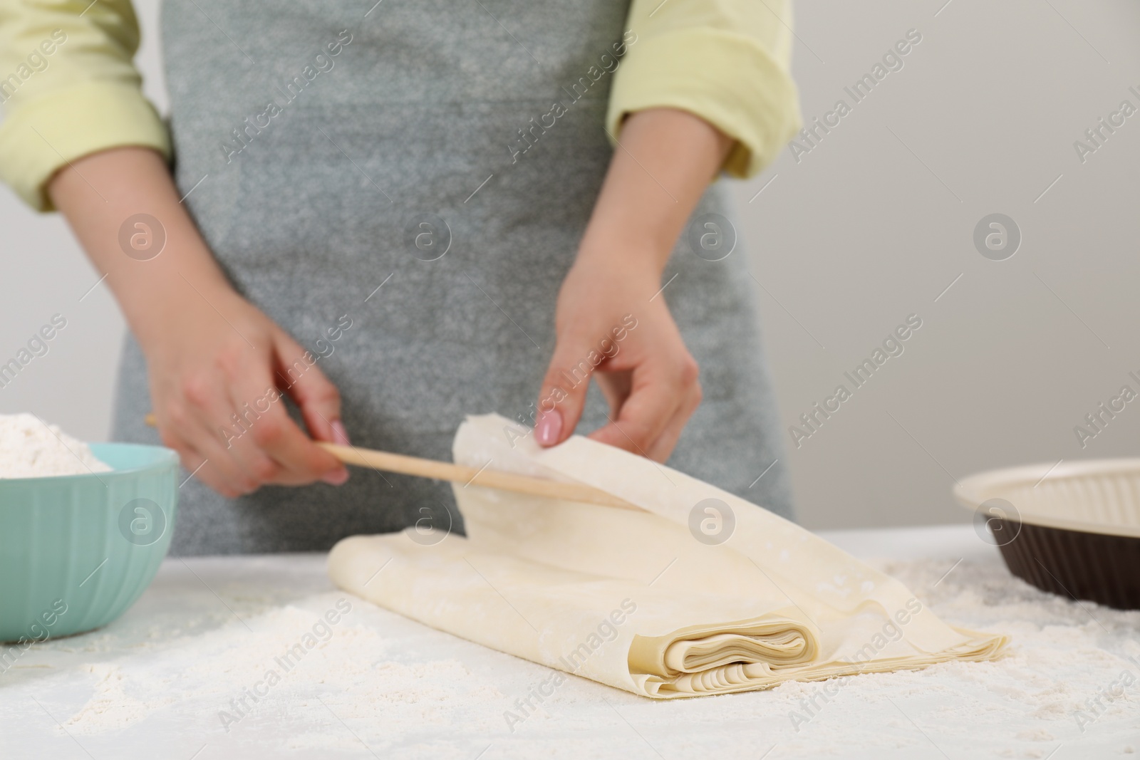 Photo of Making tasty baklava. Woman with dough at table, closeup