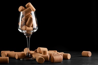Photo of Glass with wine corks on dark table. Space for text