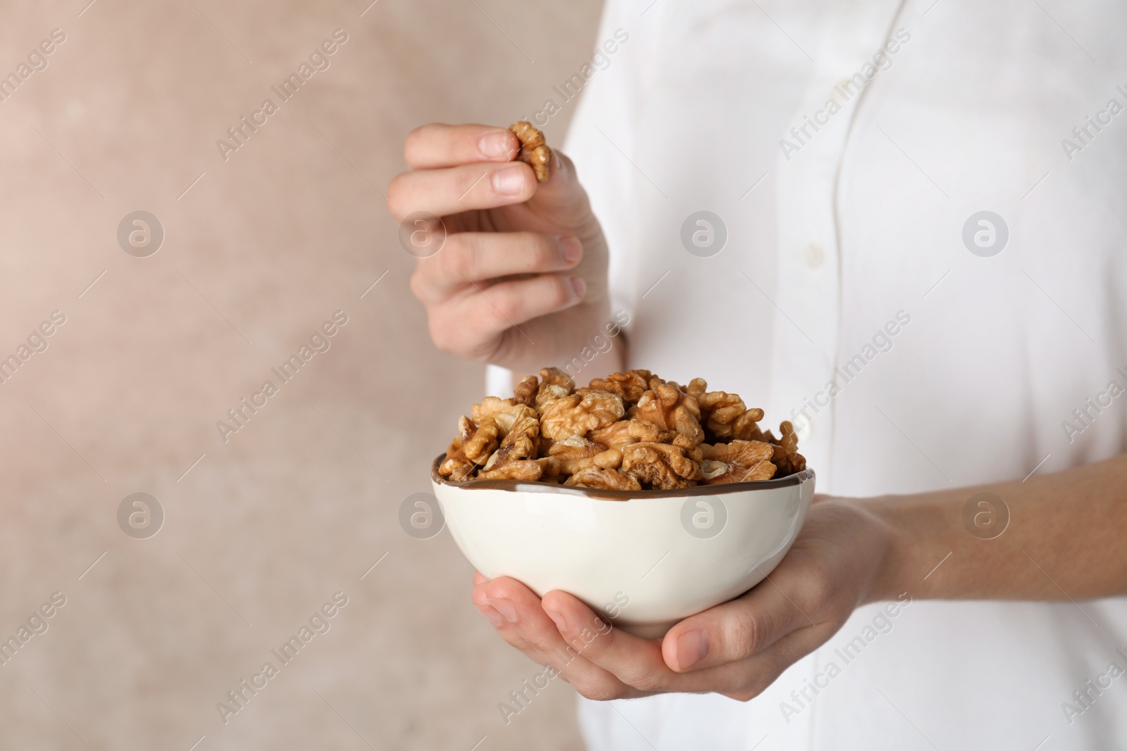 Photo of Woman holding bowl with tasty walnuts, closeup. Space for text