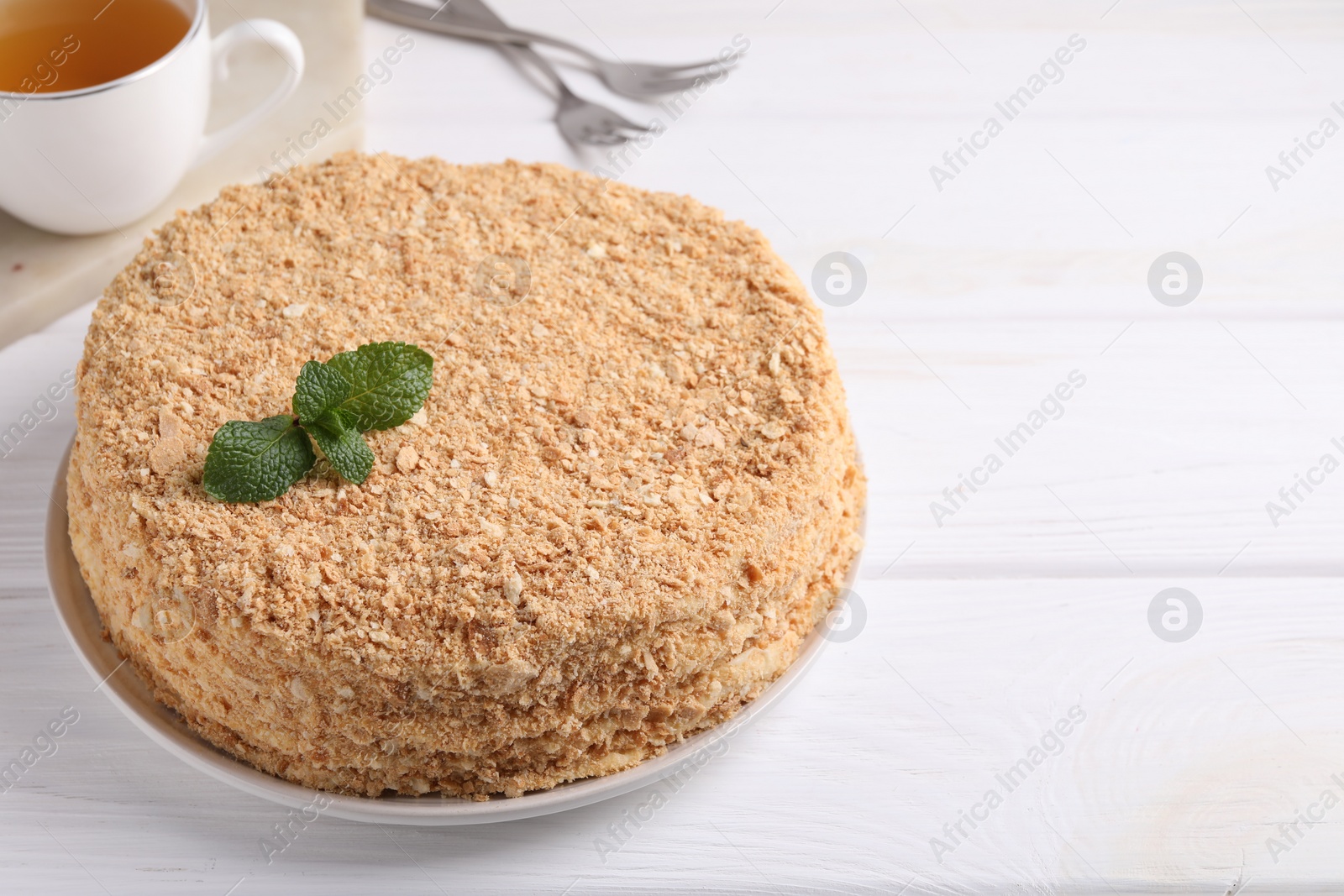 Photo of Delicious Napoleon cake served on white wooden table, closeup. Space for text