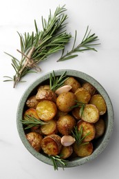 Photo of Tasty baked potato and aromatic rosemary on white marble table, flat lay