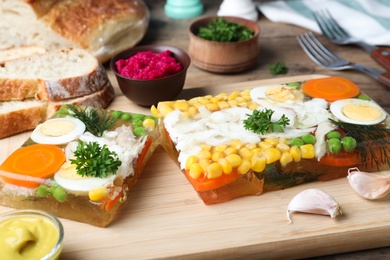 Photo of Delicious fish aspic served on wooden board, closeup