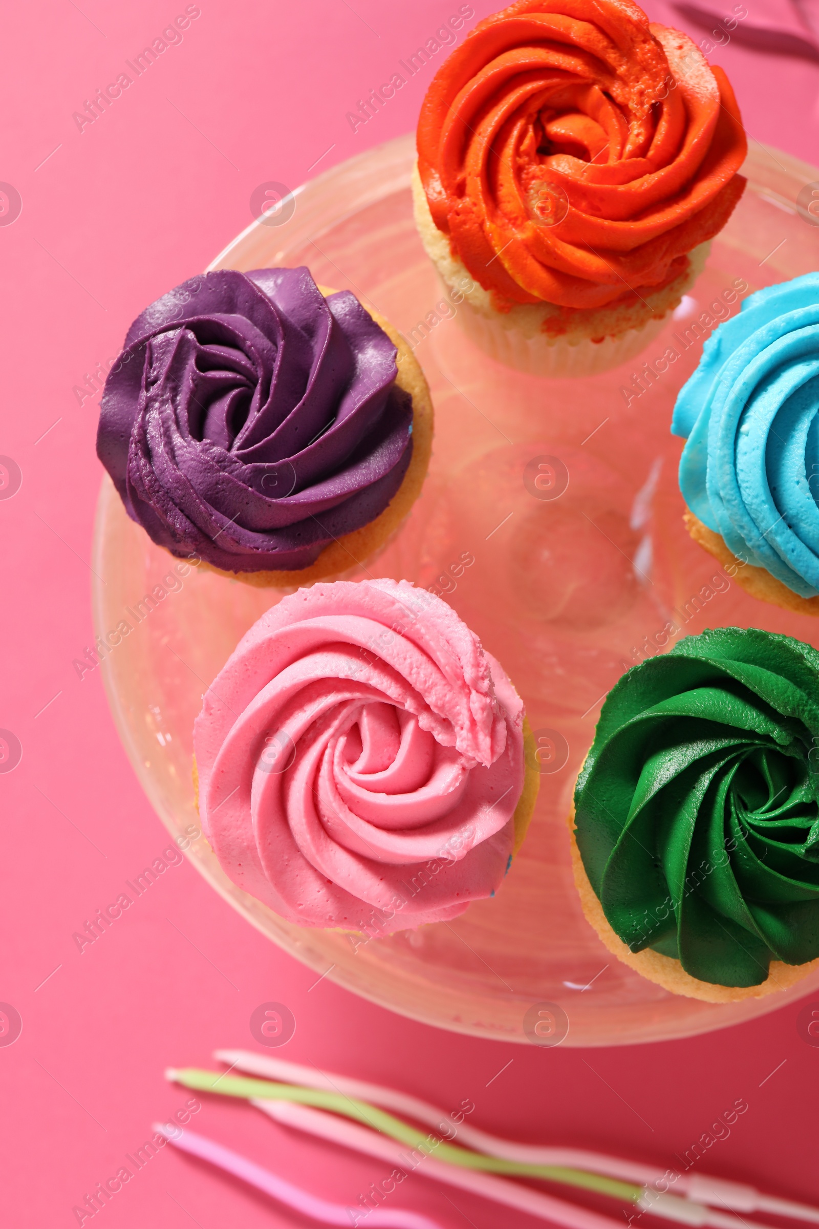 Photo of Delicious cupcakes with bright cream and candles on pink background, flat lay