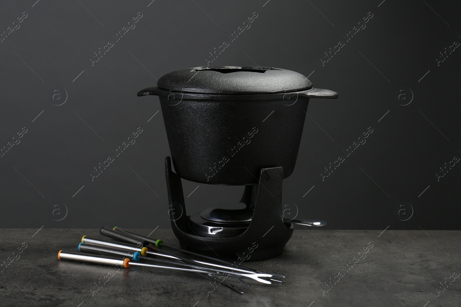 Photo of Fondue set on grey textured table. Kitchen equipment