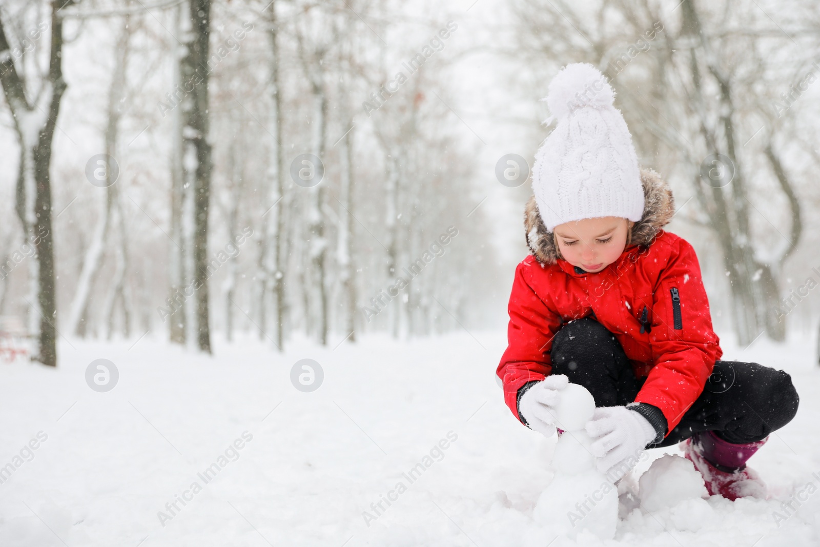 Photo of Cute little girl making snowballs outdoors on winter day, space for text