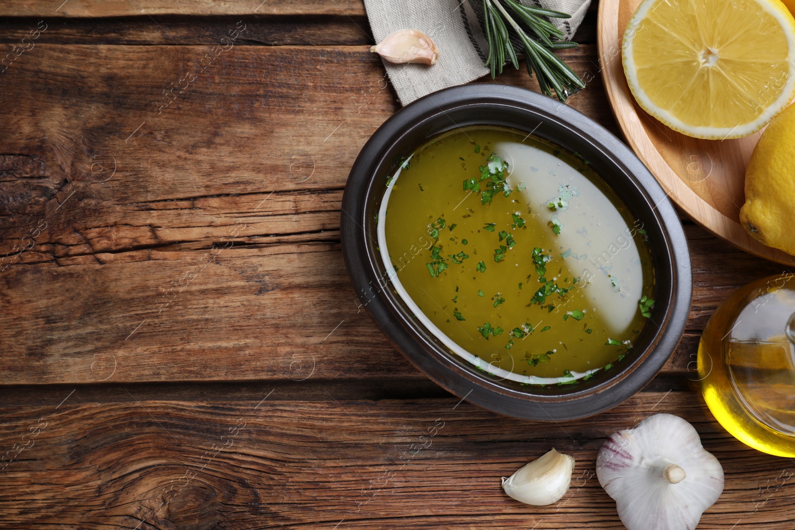 Photo of Bowl of lemon sauce and ingredients on wooden table, flat lay with space for text. Delicious salad dressing