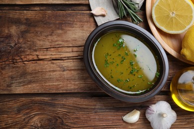 Bowl of lemon sauce and ingredients on wooden table, flat lay with space for text. Delicious salad dressing