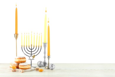Photo of Hanukkah celebration. Composition with menorah, dreidels and gift boxes on wooden table against white background