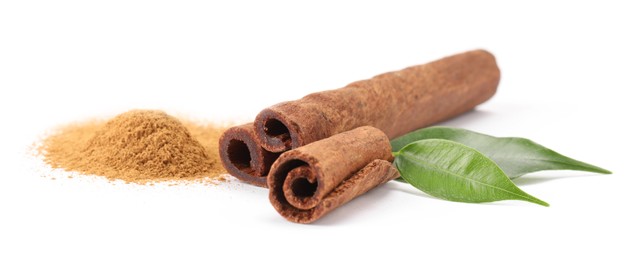 Photo of Dry aromatic cinnamon sticks, powder and green leaves isolated on white